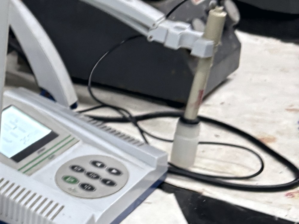 A bench meter with its probe clamped in a stand.