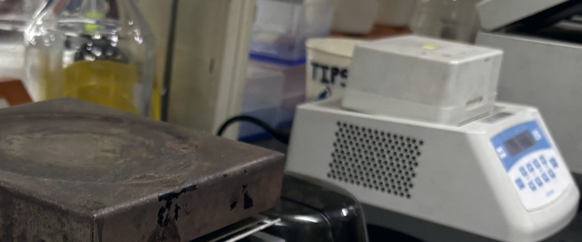 A hot plate worn smooth in the middle, beside a heating dry bath on a laboratory bench.