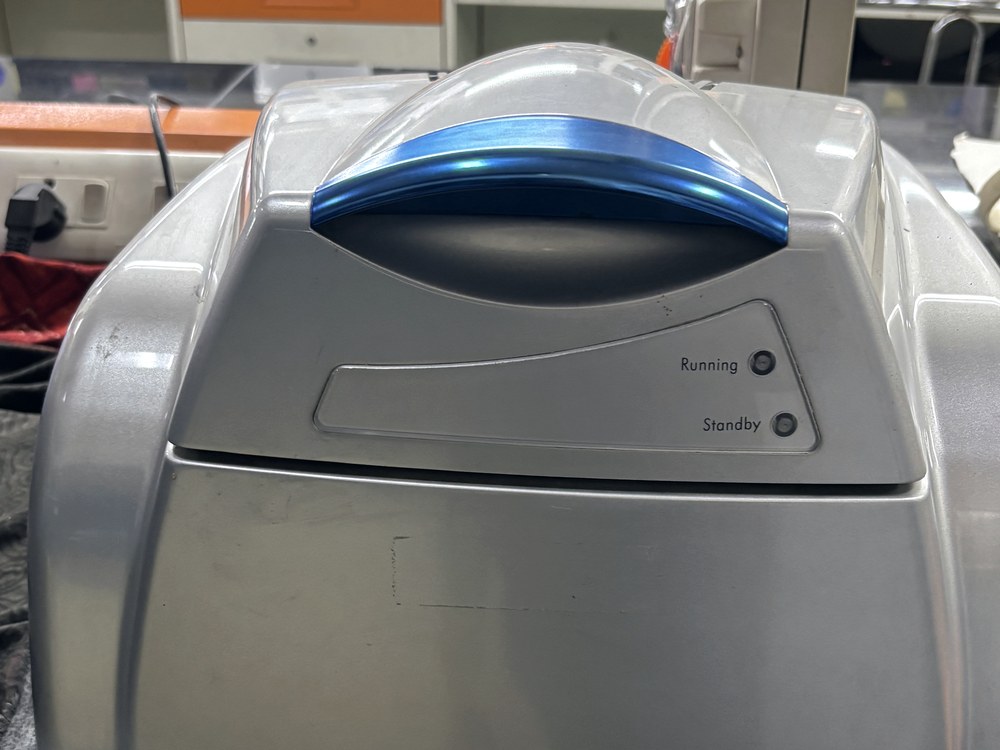 A thermal cycler with its lid lit and a cloth cover folded beside it.